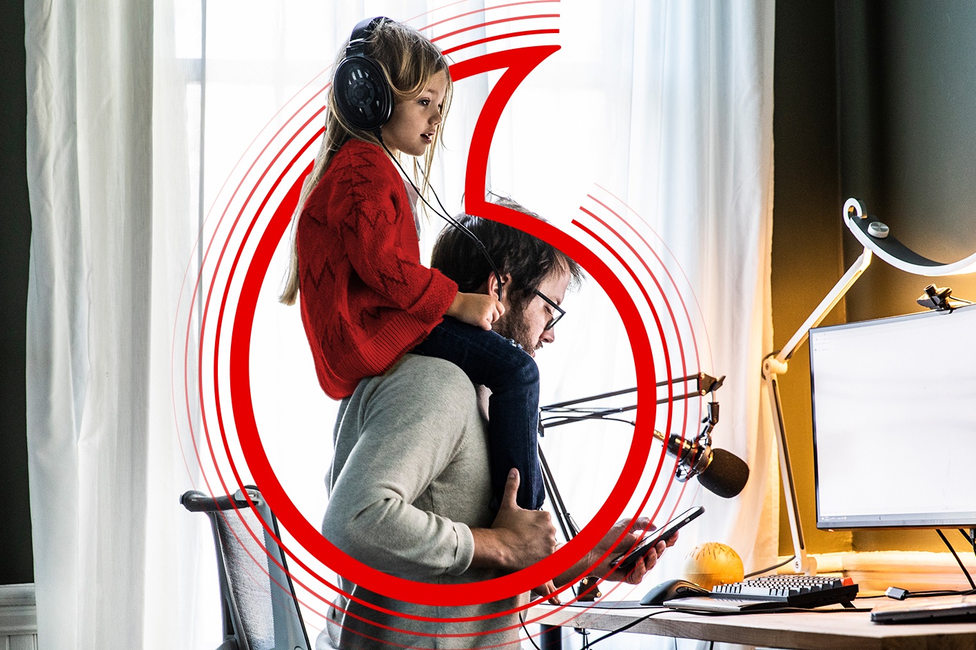 Man with daughter on shoulders sitting at desk